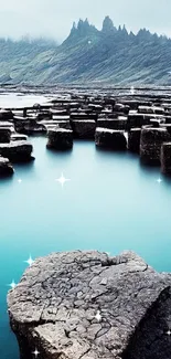 Coastal rock formations with blue water and mountain view.