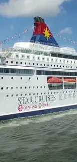 Cruise ship sailing under a bright blue sky with gentle waves.