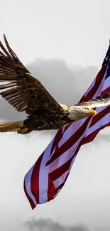 Eagle flying over American flag with cloudy sky.