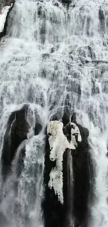 Majestic frozen waterfall cascading over rocks in a serene winter scene.