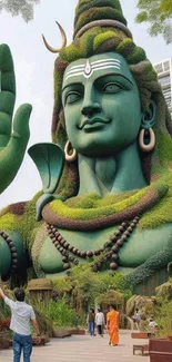 Majestic green statue of Shiva amidst nature on a mobile wallpaper.