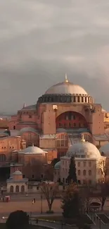 Hagia Sophia at sunset with domes and minarets, bathed in warm golden light.