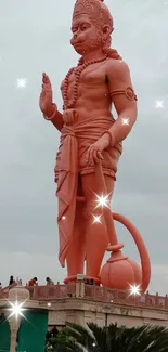 Majestic Hanuman statue with lush greenery and cloudy sky background.