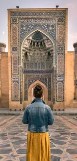 Person standing before intricate historical monument during sunset.