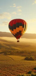 Colorful hot air balloon drifting over sunlit hills and valleys.