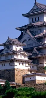 Mobile wallpaper featuring a majestic Japanese castle under a blue sky.