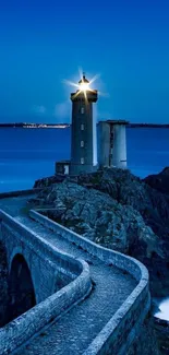 Lighthouse by the ocean at dusk with a glowing light.