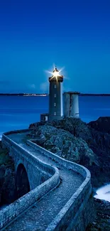 Majestic lighthouse overlooking the ocean with a winding path under a blue sky.