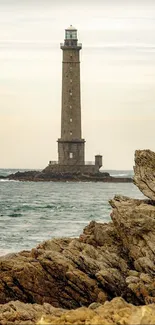 Lone lighthouse stands amid rocky coastline by the sea.