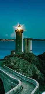 Lighthouse standing tall against a teal sky overlooking the ocean.