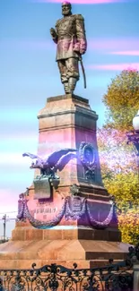 Monument with bronze statue against an autumn backdrop.