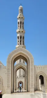 Mosque with tall minaret and arches on a clear blue sky.