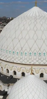 White mosque dome under a clear blue sky, showcasing intricate patterns.