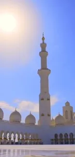 Majestic mosque under a vibrant blue sky with a bright sun overhead.