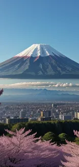 Mount Fuji with cherry blossoms and cityscape, under a clear blue sky.