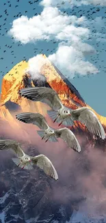 Snow-capped mountain with birds soaring in sky at sunset.