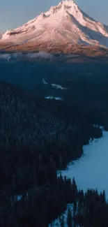 Snow-capped mountain at dusk with forest and river.