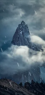 Mountain peak surrounded by misty clouds on a serene, blue-gray backdrop.