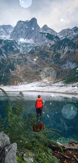 Person standing by a tranquil mountain lake with snowy peaks and lush greenery.