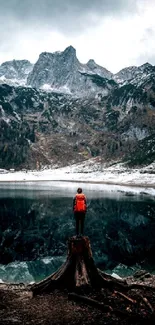 Lone adventurer at mountain lake with snow-capped peaks.