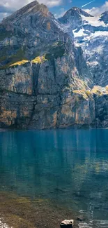 A serene mountain lake with clear blue water and towering rugged cliffs.