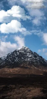 Snow-capped mountain under a blue sky with white clouds.