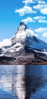 Majestic snowy mountain reflecting in a clear blue lake under a sky with white clouds.