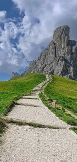 Pathway leading to rocky mountain peaks under a cloudy sky.