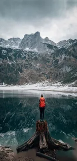 Person with orange backpack by mountain lake.