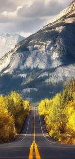 Mountain road with golden autumn trees under a cloudy sky.