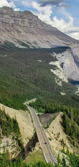 Scenic mountain road through lush forests under blue sky.