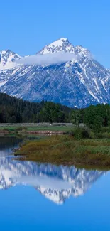 Snow-capped mountains reflecting in blue waters under a clear sky.