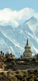 Stupa with snow-capped mountains in the background, under a clear blue sky.