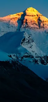 Vibrant sunrise over a majestic snowy mountain peak against a deep blue sky.