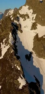 Sunrise illuminating snowy mountain peaks and rocky cliffs.