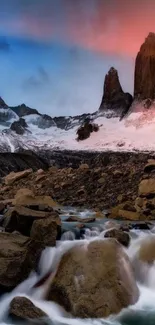 Majestic mountain sunset with vibrant sky and flowing stream.