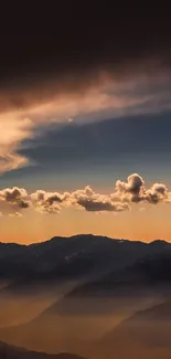 Golden sunset over mountains with clouds and silhouetted peaks.