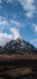 Snow-capped mountain under a blue sky with clouds.