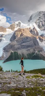 Hiker overlooking a turquoise glacial lake and snow-capped mountains.