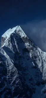 Snow-covered mountain peak against a dark blue sky.