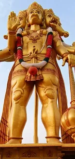 Majestic golden statue with multiple hands against a blue sky.