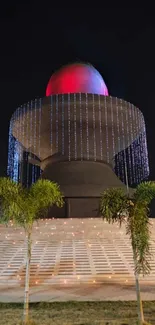 Majestic sculpture illuminated at night with vibrant lights and surrounding trees.