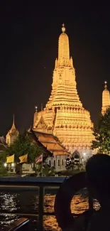 Illuminated temple at night with reflection on water.