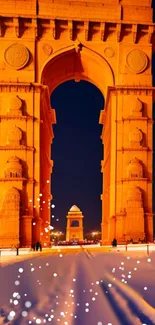 Illuminated arch monument at night, snowflakes in the foreground.