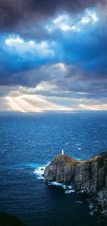 Lighthouse on cliff with dramatic ocean view under cloudy sky.