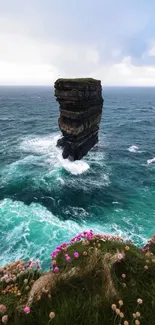 Majestic ocean cliff with waves crashing and wildflowers in the foreground.