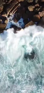 Aerial view of ocean waves crashing on rocky coastline, creating white foam.