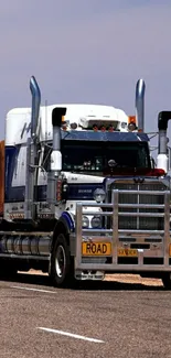 Majestic road train on a highway under a clear blue sky, ideal for mobile wallpaper.