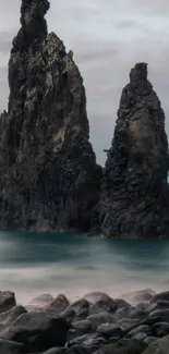 Majestic rock formations emerging from the ocean against a gray sky.