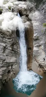 Waterfall cascading between rocky cliffs with mist and green hues.